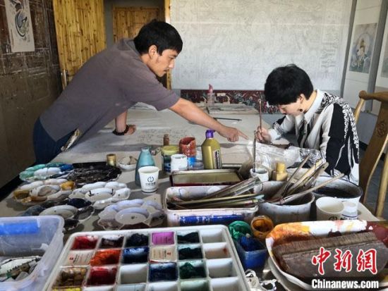 圖為2020年8月下旬，敦煌“80后”畫家張杰龍(左)在為云南麗江“學(xué)生”莫北講解敦煌壁畫的繪畫技巧?！●T志軍 攝