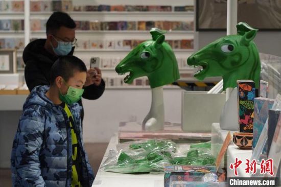 圖為“神馬來(lái)了”銅奔馬頭套吸引參觀者駐足?！【琶赖┰?攝