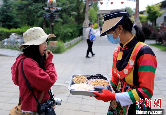 圖為身穿土族服飾的女性介紹當(dāng)?shù)靥厣〕浴！⊙Φ?攝