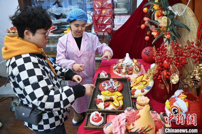 1月25日，隨著春節(jié)臨近，蘭州一花饃店“龍”元素花饃熱銷。圖為工作人員向顧客推薦“龍”元素花饃。九美旦增 攝</p><p>