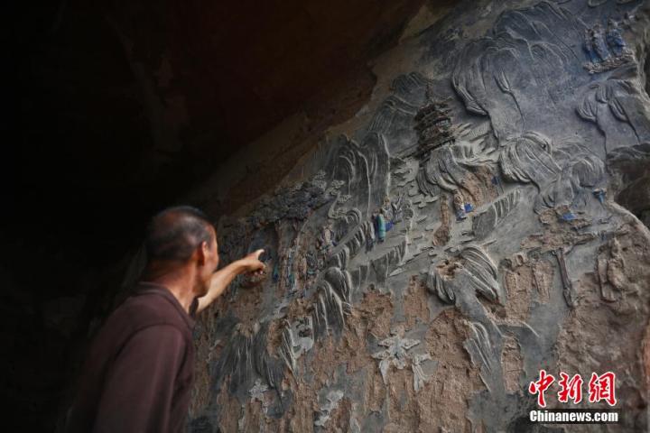 7月15日，甘肅省平?jīng)鍪袥艽h百里石窟長廊羅漢洞石窟內(nèi)，該窟文保員郭建平介紹窟內(nèi)石刻彩繪壁畫。郭建平家中三代人曾自發(fā)保護羅漢洞石窟。羅漢洞石窟遺存40余個窟龕，以北魏至清代風(fēng)格為主。中新社記者 李亞龍 攝