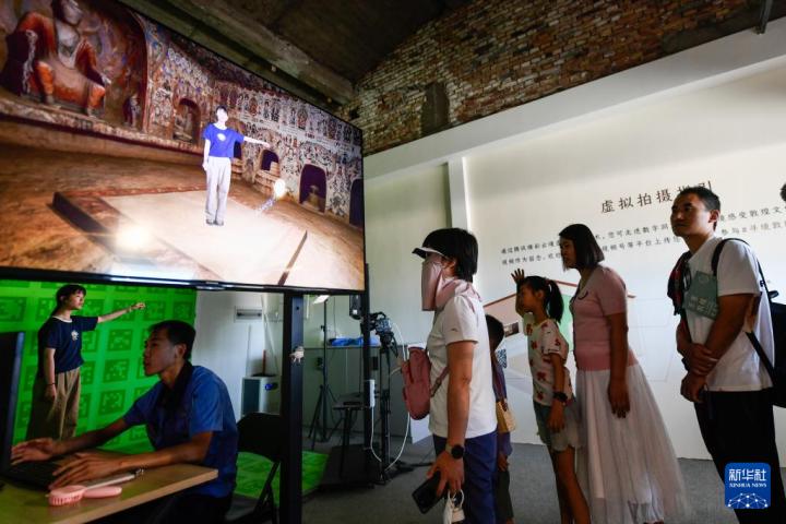 7月22日，游客體驗“尋境敦煌——數(shù)字敦煌沉浸展”后，在虛擬演播廳拍攝一段真人與洞窟虛擬場景交互的視頻。新華社記者 郎兵兵 攝</p>
<p>