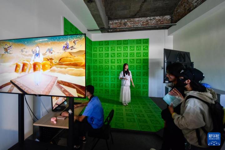 7月22日，游客體驗“尋境敦煌——數(shù)字敦煌沉浸展”后，在虛擬演播廳拍攝一段真人與洞窟虛擬場景交互的視頻。新華社記者 郎兵兵 攝</p>
<p>